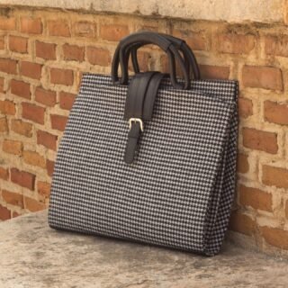 The Houndstooth Sartorial Black Leather Briefcase blends sleek black leather with classic houndstooth fabric. Handcrafted in Spain, it’s perfectly sized at 13 x 16.5 x 2 inches to carry your laptop, documents, and daily essentials—making it a stylish yet practical choice for modern professionals.